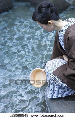 Mature Adult Woman Scooping Hot Spring Water with a Wooden Pail, Side View, High Angle View, Three Quarter Length View Large Photo Image Stock Photo - Mature Adult Woman Scooping Hot Spring Water with a Wooden Pail, Side View, High Angle View, Three Quarter Length. Fotosearch