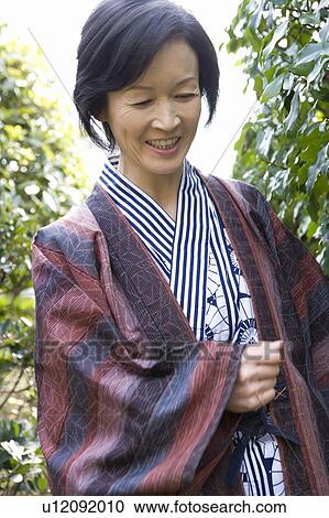 Stock Image - Mature Adult Woman Wearing Yukata, Front View, Waist Up, Low Angle View. Fotosearch