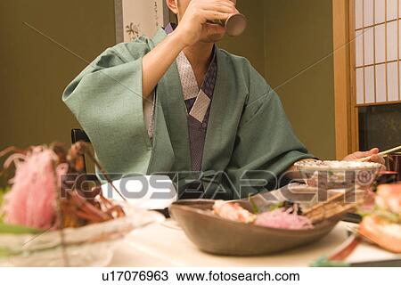 Stock Image - A Man in Yukata, Drinking, Low Angle View, Close Up. Fotosearch
