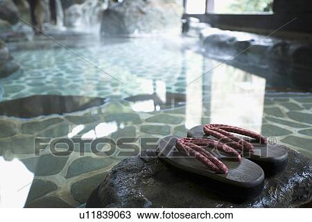 Stock Image - Image of a Japanese Outdoor Hot Spring Bath, Wooden Clogs at the Side, Close Up, High Angle View. Fotosearch