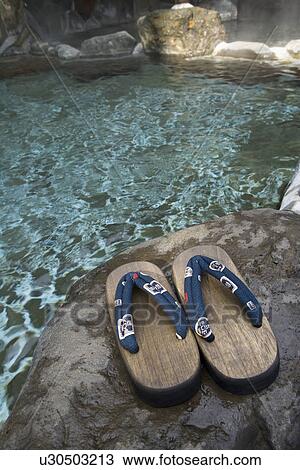 Stock Image - Image of a Japanese Outdoor Hot Spring Bath, Wooden Clogs at the Side, Close Up, High Angle View. Fotosearch
