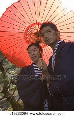 Mid Adult Couple in Yukata, Under a Red Umbrella, Low Angle View View Large Photo Image Picture - Mid Adult Couple in Yukata, Under a Red Umbrella, Low Angle View. Fotosearch