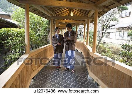 Stock Photograph - Mid Adult Couple in Yukata, Walking on the Outside Corridor, Front View. Fotosearch