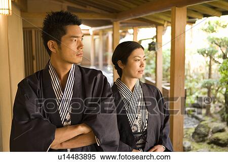 Stock Photography - Mid Adult Couple in Yukata, Walking on the Outside Corridor, Looking at the Japanese Garden, Front View. Fotosearch