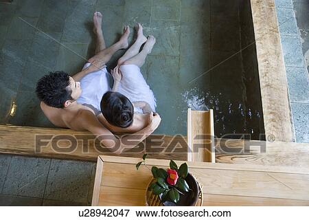 Stock Photo - Mid Adult Couple Soaking in the Hot Spring Bath Together, High Angle View. Fotosearch