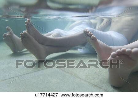 Stock Photo - Man's and women's legs in a hot tub, side view, Japan. Fotosearch