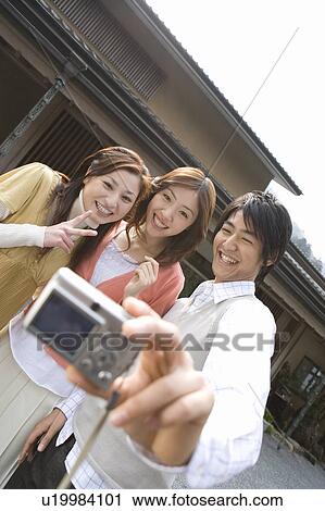 Three young people taking a picture of themselves, front view, Japan View Large Photo Image Stock Image - Three young people taking a picture of themselves, front view, Japan. Fotosearch