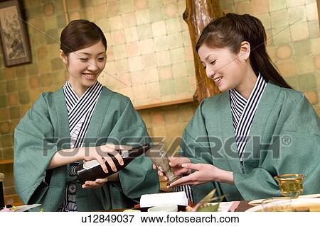 Two women having dinner, holding a beer bottle and a glass, front view, Japan View Large Photo Image Stock Photo - Two women having dinner, holding a beer bottle and a glass, front view, Japan. Fotosearch