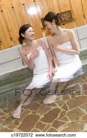 Stock Image - Two women in a hot tub, front view, Japan. Fotosearch