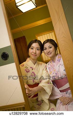 Stock Photo - Two women in Yukata sitting and sliding the door, front view, Japan. Fotosearch