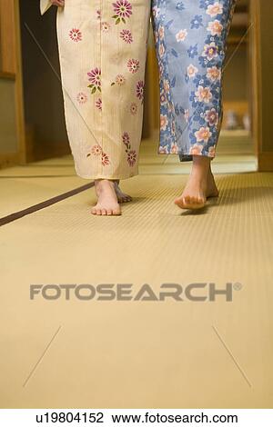 Stock Image - Two women in Yukata walking on Tatami mats, front view, copy space, Japan. Fotosearch