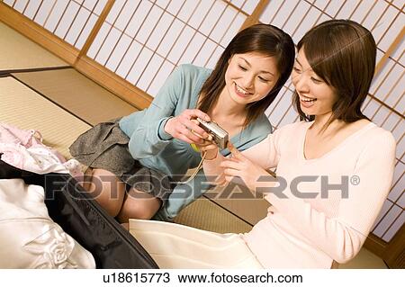 Two women looking at a digital camera in the room, front view, Japan View Large Photo Image Stock Image - Two women looking at a digital camera in the room, front view, Japan. Fotosearch