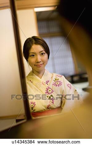 Picture - Woman in Yukata looking at the mirror, reflected in the mirror, front view, Japan. Fotosearch