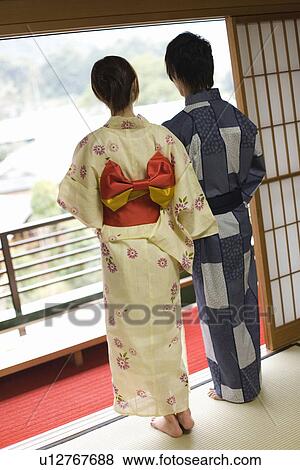 Stock Photo - Young couple in Yukata looking outside from the window, rear view, Japan. Fotosearch