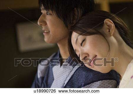 Stock Photograph - Young couple in Yukata, woman leaning her head on man's shoulder, side view, close up, Japan. Fotosearch