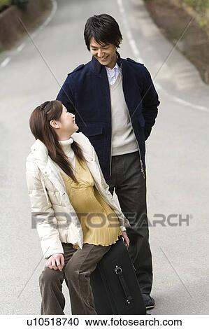 Young couple on the road, woman sitting on a suitcase, front view, Japan View Large Photo Image Stock Image - Young couple on the road, woman sitting on a suitcase, front view, Japan. Fotosearch