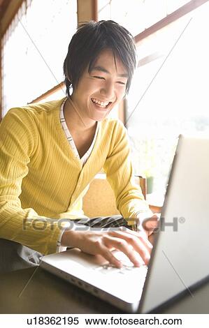 Young man smiling and using a laptop, front view, Japan View Large Photo Image Stock Photography - Young man smiling and using a laptop, front view, Japan. Fotosearch