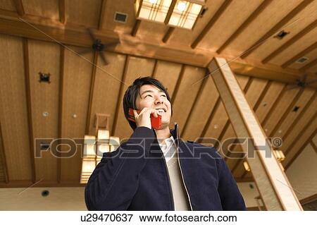Stock Photo - Young man using a mobile phone in a Japanese inn, low angle view, Japan. Fotosearch
