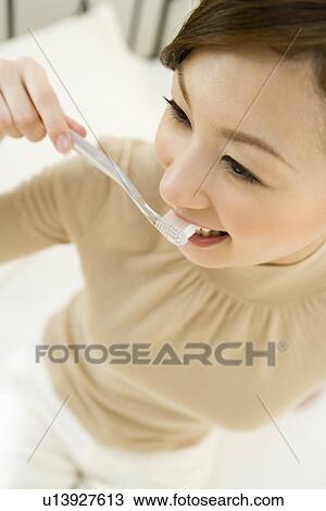Stock Image - A woman brushing teeth, high angle view, close up, differential focus. Fotosearch