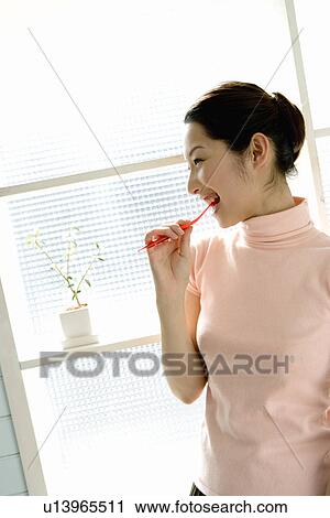 A woman brushing teeth, smiling, side view View Large Photo Image Stock Image - A woman brushing teeth, smiling, side view. Fotosearch