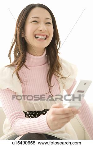 A woman laughing and holding a mobile phone, front view, white background View Large Photo Image Stock Photo - A woman laughing and holding a mobile phone, front view, white background. Fotosearch