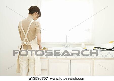 A woman standing in the kitchen, rear view View Large Photo Image Stock Photo - A woman standing in the kitchen, rear view. Fotosearch