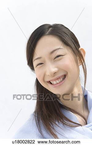 Stock Image - Portrait of a woman smiling, looking at camera, front view, white background. Fotosearch