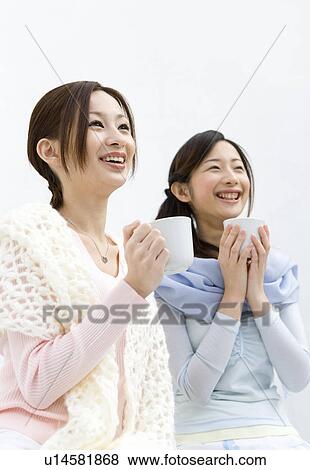Two women smiling and holding cups, front view, side view, white background, low angle view View Large Photo Image Stock Photo - Two women smiling and holding cups, front view, side view, white background, low angle view. Fotosearch