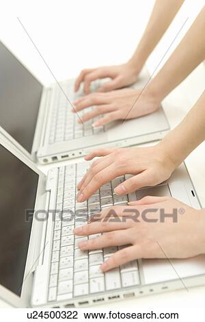 Two women typing on a laptops, side view, white background, close up View Large Photo Image Stock Image - Two women typing on a laptops, side view, white background, close up. Fotosearch