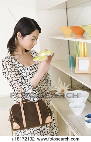 Stock Image - Woman enjoying shopping, smiling, side view. Fotosearch