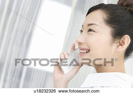 Woman smiling and using mobile phone, side view View Large Photo Image Stock Photograph - Woman smiling and using mobile phone, side view. Fotosearch