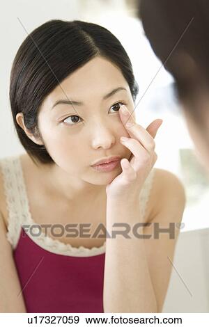 Stock Photo - Young Woman Inserting Contact Lens, Front View . Fotosearch