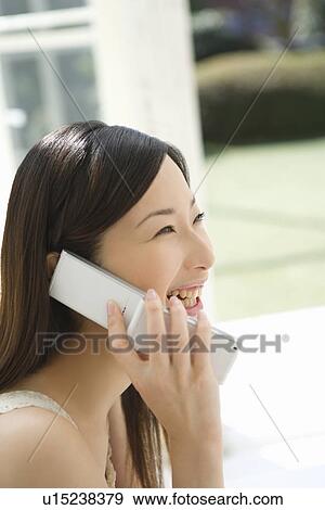 Young Woman Using a Mobile Phone, Looking Away, Smiling, Side View View Large Photo Image Stock Photo - Young Woman Using a Mobile Phone, Looking Away, Smiling, Side View . Fotosearch