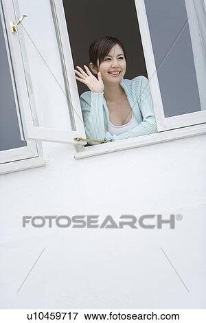 A Smiling Young Woman Looking Outside the Window, Waving Right Hand, Low Angle View View Large Photo Image Stock Photo - A Smiling Young Woman Looking Outside the Window, Waving Right Hand, Low Angle View. Fotosearch