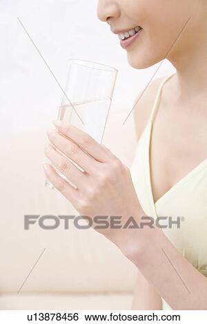 Stock Photograph - A Young Woman Drinking Glass of Water, Side View, Close Up, No Face. Fotosearch