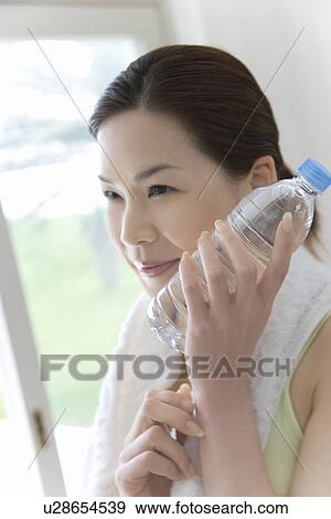 A Young Woman Holding A Water Bottle, Cooling Her Cheek, Side View View Large Photo Image Stock Photo - A Young Woman Holding A Water Bottle, Cooling Her Cheek, Side View. Fotosearch
