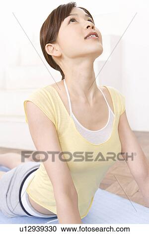Stock Image - A Young Woman Practicing Yoga, Laying on Her Stomach, Side View. Fotosearch