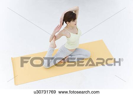 A Young Woman Practicing Yoga, Sitting and Putting Her Arms Behind the Head, High Angle View View Large Photo Image Stock Photo - A Young Woman Practicing Yoga, Sitting and Putting Her Arms Behind the Head, High Angle View. Fotosearch