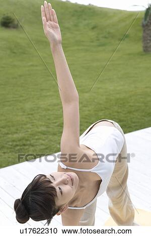 Stock Image - A Young Woman Stretching Outside, High Angle View. Fotosearch