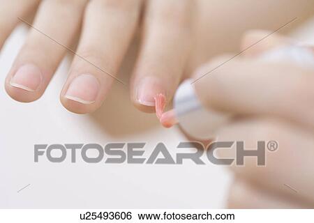 Stock Photograph - Close-up Image of A Young Woman Putting Nail Color on Fingers, High Angle View, No Face, Differential Focus. Fotosearch