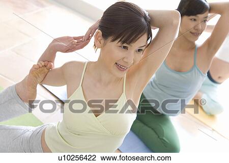 Stock Image - Three Young Women Practicing Yoga, Arms Behind the Head, High Angle View. Fotosearch