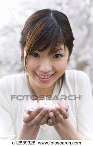 肖像画 の A 若い女性 すくう の上 さくらんぼ 花 で 手 微笑 そして カメラを見る 正面図 日本 写真館 イメージ館 U Fotosearch
