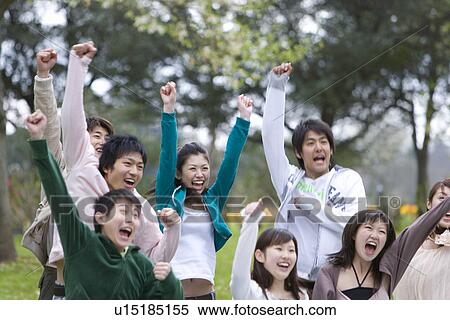 Stock Photography - Medium group of young people holding fists up in the air, cheering, front view, Japan. Fotosearch