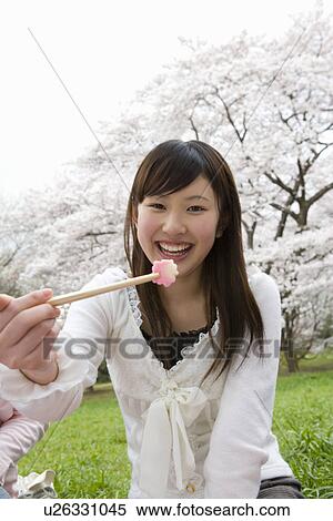 Portrait of a woman enjoying lunch surrounded with cherry blossoms, smiling and looking at camera, front view, Japan View Large Photo Image Stock Photography - Portrait of a woman enjoying lunch surrounded with cherry blossoms, smiling and looking at camera, front view, Japan. Fotosearch