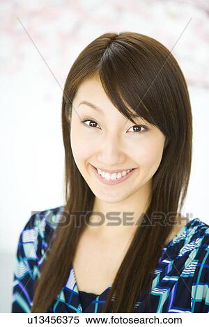 Stock Photography - Portrait of a woman smiling and looking at camera, front view, Japan. Fotosearch