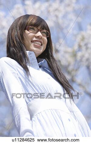 Woman smiling and standing under the cherry tree, low angle view, Japan View Large Photo Image Stock Photography - Woman smiling and standing under the cherry tree, low angle view, Japan. Fotosearch
