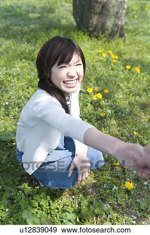 Young Woman smiling and holding arm up on lawn, high angle view, Japan View Large Photo Image Stock Photo - Young Woman smiling and holding arm up on lawn, high angle view, Japan. Fotosearch