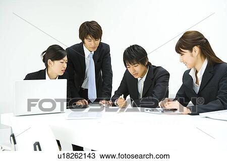 Stock Image - Four young business people in meeting, front view, side view, white background, Japan. Fotosearch
