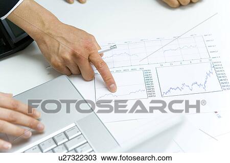 Stock Image - Two young businessmen in meeting, files and laptop on table, high angle view, Japan. Fotosearch