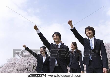 Picture - Young business people punching air at the field of cherry blossoms, low angle view, Japan. Fotosearch